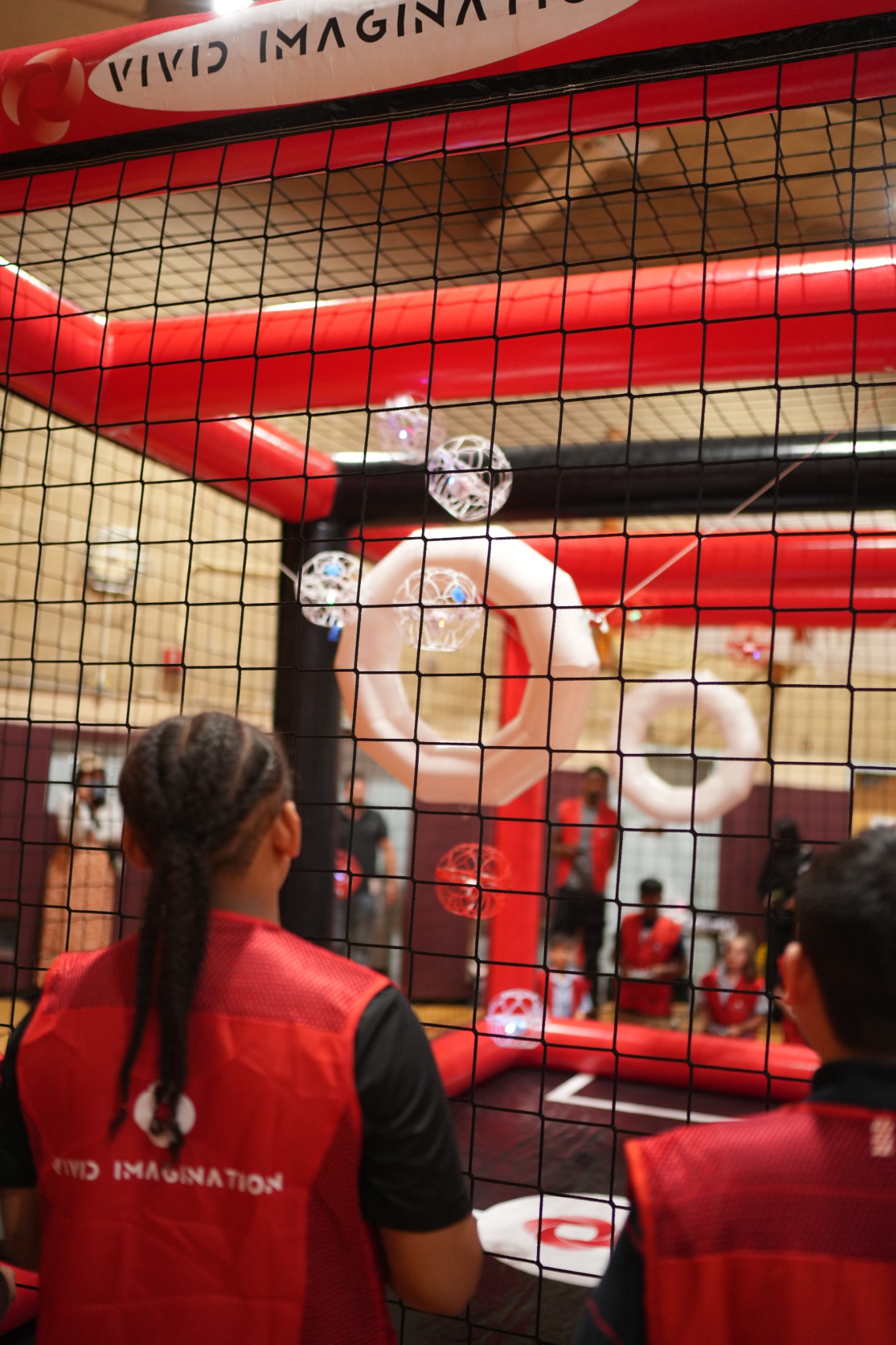 Students piloting caged drones inside a Vivid Imagination Drone Soccer arena